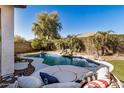 An inviting backyard pool features a custom rock waterfall and tanning deck surrounded by lush landscaping at 17704 W Tasha Dr, Surprise, AZ 85388