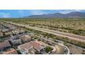 An aerial view of a house in a neighborhood near a natural desert landscape with distant mountain views at 19057 W Yucatan Dr, Surprise, AZ 85388