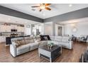 Open-concept living room with hardwood floors, a ceiling fan, and a large sectional sofa at 26020 N 138Th Ln, Peoria, AZ 85383