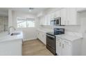 Modern kitchen with white cabinets, stainless steel appliances, marble countertops, and wood-look flooring at 2728 W Redfield Rd, Phoenix, AZ 85053