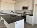 Modern kitchen featuring white cabinets, stainless steel appliances, and a dark countertop island at 31512 N Hayweather Ln, San Tan Valley, AZ 85143