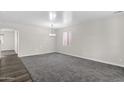 Spacious living room featuring neutral paint, modern lighting, and plush carpeting at 43524 W Bailey Dr, Maricopa, AZ 85138