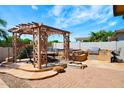 Backyard with pergola, outdoor dining table, built-in grill, spa, fire pit and paved patio at 4488 N 155Th Ave, Goodyear, AZ 85395