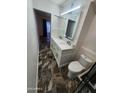 Modern bathroom with double sink vanity, lighted mirror and neutral colored stone-look floors at 5228 N 15Th Dr, Phoenix, AZ 85015