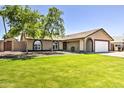 Charming single-story home with a lush green lawn, mature trees, and an arched entrance to the two-car garage at 8037 W Sweetwater Ave, Peoria, AZ 85381