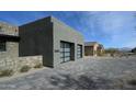 Contemporary home exterior shows a gray stucco facade with a spacious two-car garage and modern glass doors at 12856 E Rosewood Dr, Scottsdale, AZ 85255