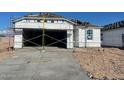 View of an exterior elevation of a home under construction, including a two car garage and unfinished landscaping at 1317 S Vista Ave, Florence, AZ 85132