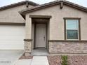 Close-up view of front entrance with stone accents around the doorway and window at 17426 W Eva St, Waddell, AZ 85355