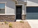 Charming home featuring a black front door, stone accents, and landscaped front yard at 17434 W Eva St, Waddell, AZ 85355
