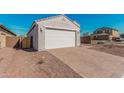 A two-car garage with a brick paver driveway, and low-maintenance desert landscaping at 6722 W Desert Dr, Laveen, AZ 85339
