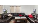 Comfortable living room featuring a leather sectional sofa, tile floors, and natural light from the window at 11101 N 82Nd Dr, Peoria, AZ 85345