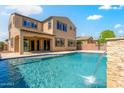 Resort-style backyard with a large swimming pool, waterfall feature, and covered patio area at 16074 W Cortez St, Surprise, AZ 85379