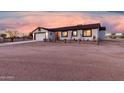 Single-story home with rustic wood fence and two-car garage, set against a vibrant sunset backdrop at 20438 W Carver Rd, Buckeye, AZ 85326