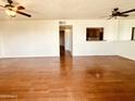 Spacious living room featuring ceiling fans, wood floors, and a view into the kitchen at 240 S Old Litchfield Rd # 206, Litchfield Park, AZ 85340