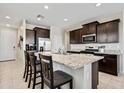 Modern kitchen featuring dark wood cabinets, stainless steel appliances, granite countertops and a large island with seating at 2466 E Rosario Mission Dr, Casa Grande, AZ 85194