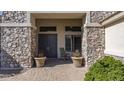 Stone accented entry way with double doors, potted plants, and covered seating area at 56 S Prairie Rd, Gilbert, AZ 85296