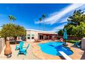 Backyard has a pool, covered patio with lounge furniture, lush landscaping and an orange tree at 6707 E Aire Libre Ln, Scottsdale, AZ 85254