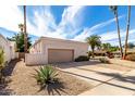 Exterior showcasing a desert-landscaped front yard, covered in decorative rocks, native vegetation, and palm trees at 6707 E Aire Libre Ln, Scottsdale, AZ 85254