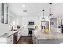 Bright kitchen features white cabinets, stainless appliances, granite counters and an island with pendant lighting at 6707 E Aire Libre Ln, Scottsdale, AZ 85254