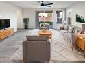 Bright living room with modern furniture, a ceiling fan, and a sliding glass door at 16416 W Cottontail Ln, Surprise, AZ 85387