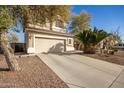 Two-story home featuring a large driveway, desert landscaping, and a neutral color palette at 21487 N Greenway Rd, Maricopa, AZ 85138