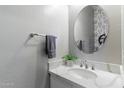 Charming powder room features a white vanity with a marble countertop and round mirror at 23065 N 75Th St, Scottsdale, AZ 85255