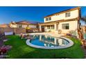 Backyard oasis features a sparkling pool, lush artificial turf, and a covered patio at 26312 N 132Nd Ln, Peoria, AZ 85383