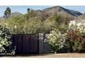 Gated entry with desert landscaping featuring flowers and mountains in the background at 6323 E Gold Dust Ave, Paradise Valley, AZ 85253
