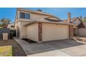 Two-story home with a brick-trimmed, two-car garage and a well-maintained lawn under a bright, cloudless sky at 6405 W Saguaro Dr, Glendale, AZ 85304