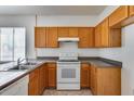 Functional kitchen with stainless steel sink, white appliances, and tile flooring at 6557 W Puget Ave, Glendale, AZ 85302