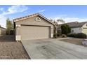 A tan house with a two-car garage and desert landscaping in front of the home at 8434 E Natal Cir, Mesa, AZ 85209