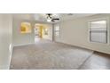 A large, open living room with neutral carpet, ceiling fan, and natural light at 8434 E Natal Cir, Mesa, AZ 85209