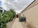 Side yard with a tiled walkway, stucco wall, and green foliage at 10323 W Carousel Dr, Arizona City, AZ 85123