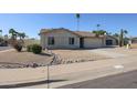 Tan single-story home featuring a two-car garage and low-maintenance desert landscaping near the sidewalk at 10720 E Sahuaro Dr, Scottsdale, AZ 85259