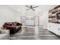 Spacious living room showcasing gray wood floors, a ceiling fan, and large windows for abundant natural light at 11843 W Cambridge Ave, Avondale, AZ 85392