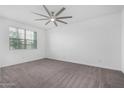 Clean, bright bedroom with neutral carpet flooring, a ceiling fan, and a window at 22679 E Estrella Rd, Queen Creek, AZ 85142