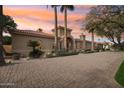 Elegant home featuring a grand entrance, lush landscaping and a spacious brick driveway, set against a vibrant sunset at 5827 E Sanna St, Paradise Valley, AZ 85253