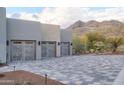 Three-car garage with wooden doors and patterned stone driveway, set against a mountain backdrop at 6038 E Agave Cir, Carefree, AZ 85377