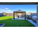 A covered gazebo, table, and chairs adorn this backyard with artificial grass, perfect for entertaining at 17618 W Paraiso Dr, Surprise, AZ 85387