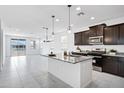 Modern kitchen features stainless steel appliances, dark wood cabinets, granite countertops, and an island with pendant lighting at 20670 N Confetti Ct, Maricopa, AZ 85138