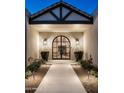 Elegant entryway with arched front door, flanked by sconces and manicured landscaping at 22619 N La Senda Dr, Scottsdale, AZ 85255