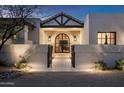 Exterior entrance featuring a black framed glass front door, desert landscaping, and modern wall lighting at 22619 N La Senda Dr, Scottsdale, AZ 85255