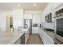 Spacious kitchen featuring white cabinetry, stainless steel appliances, and a large granite-top island at 22924 E Desert Spoon Dr, Queen Creek, AZ 85142