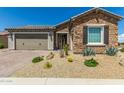 Charming home with stone accents, a two-car garage, desert landscaping, and a paved driveway at 27366 W Escuda Dr, Buckeye, AZ 85396