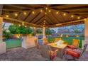 Outdoor living space featuring a covered patio with a fire pit table, bar, putting green, and backyard at 5020 E Pershing Ave, Scottsdale, AZ 85254