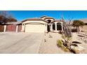 Inviting single-story home featuring desert landscaping, a spacious driveway, and a two-car garage at 6458 W Adobe Dr, Glendale, AZ 85308