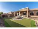 Lush backyard featuring a putting green, built-in grill, covered patio, and cozy outdoor seating at 17857 W Desert View Ln, Goodyear, AZ 85338
