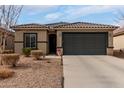 Single story home with desert landscaping, tile roof, neutral color stucco, and a large two car garage at 18644 N Desert Willow Dr, Maricopa, AZ 85138