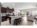 Modern kitchen with dark cabinetry, granite counters, and island seating flows into the dining and living areas at 18644 N Desert Willow Dr, Maricopa, AZ 85138