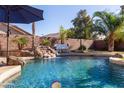 Backyard pool featuring a beautiful rock waterfall, lush greenery, and plenty of space for entertaining at 44560 W Copper Trl, Maricopa, AZ 85139